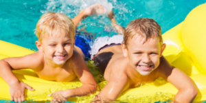 Two boys smile on a yellow pool float